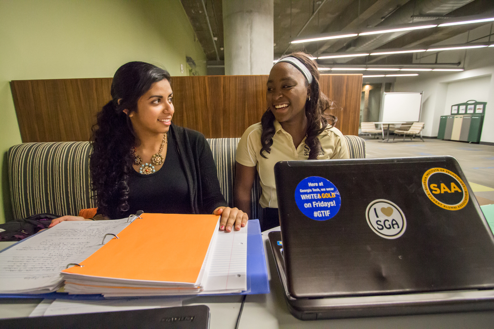 Two female students laughing while studying.